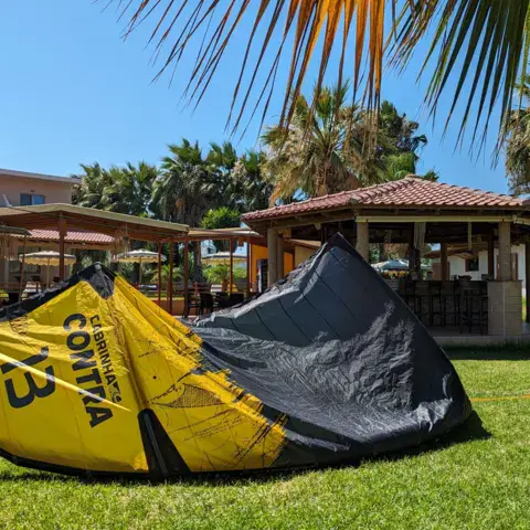 Kite jaune et noir étalé sur une pelouse, bâtiments en arrière-plan