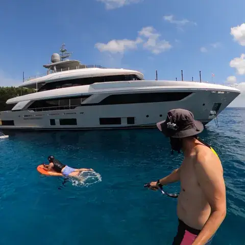 Rider sur e-foil à côté d'un yacht à l'ancre