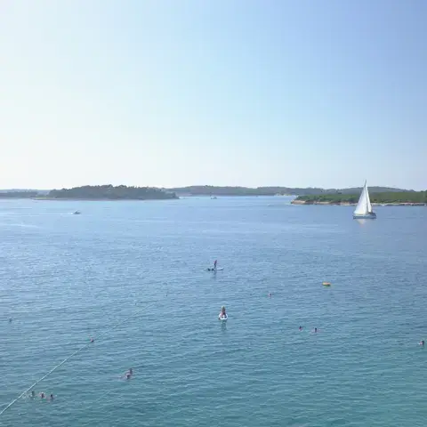 Plan d'eau calme avec voilier et îlots à l'horizon