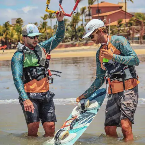 Deux moniteurs avec une planche de kitesurf dans l'eau peu profonde