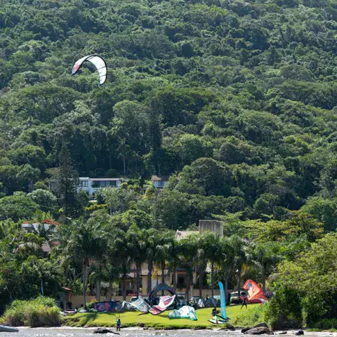 Kitesurfeur sur le plan d'eau devant un versant boisé