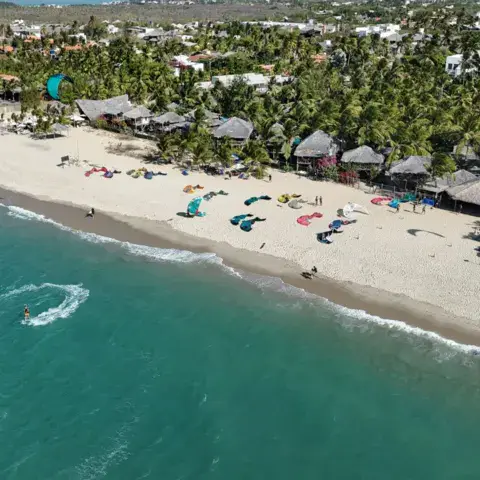 Un kitesurfeur sur l'eau turquoise devant la plage