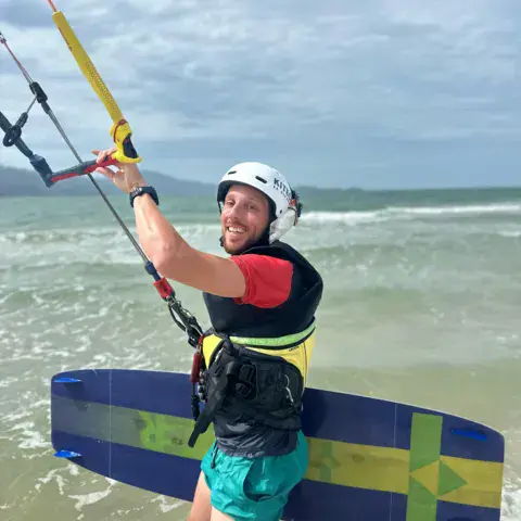 Kitesurfeur avec sa planche et sa barre dans l'eau