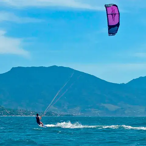 Kitesurfeur sous un kite violet devant les montagnes