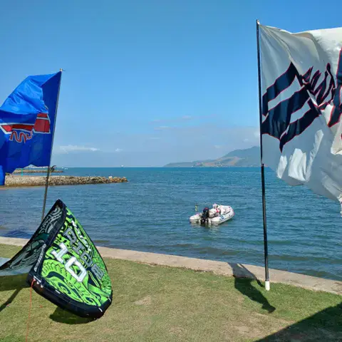 Kite posé sur la pelouse du bord de mer, drapeaux et bateau d'appui sur l'eau