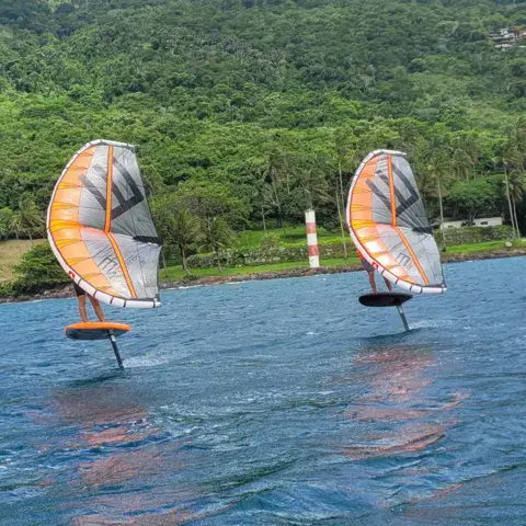 Deux riders de wingfoil en vol près du rivage