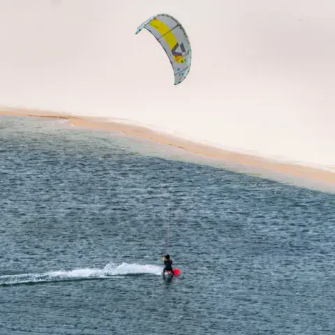 Kitesurfeur sur une lagune devant les dunes