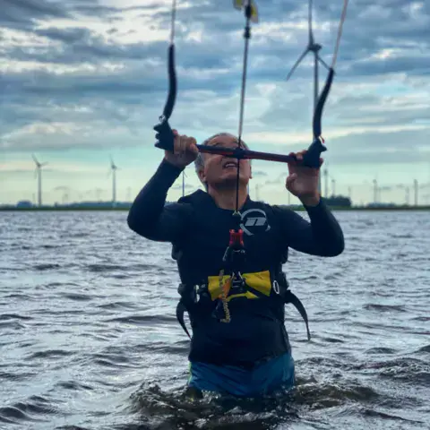 Cours de kitesurf, barre en main, de l'eau jusqu'aux hanches