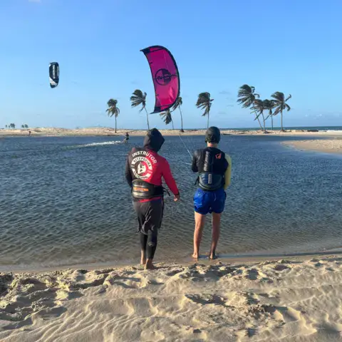 Plan d'eau plat avec kites en vol, vu depuis la rive