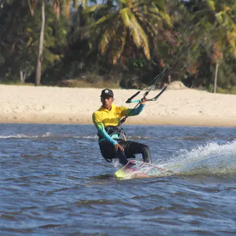 Kitesurfeur sur l'eau, palmiers sur la rive