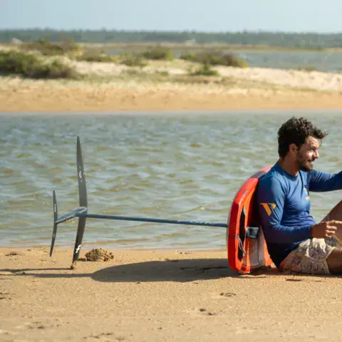 Pratiquant assis au bord de l'eau avec son matériel de foil