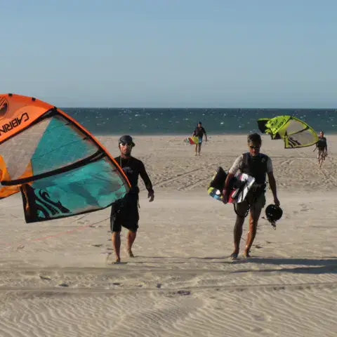 Kitesurfeurs revenant avec leurs kites sur le sable