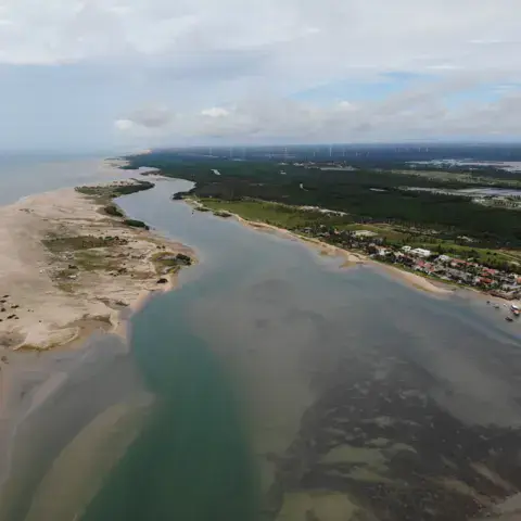 Vue aérienne d'un banc de sable, d'un chenal et d'un village côtier