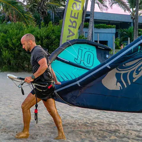 Kitesurfeur portant son aile sur la plage