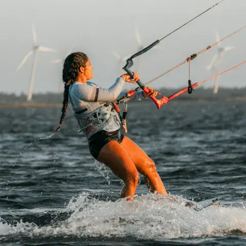Kitesurfeuse en navigation, éoliennes à l'horizon