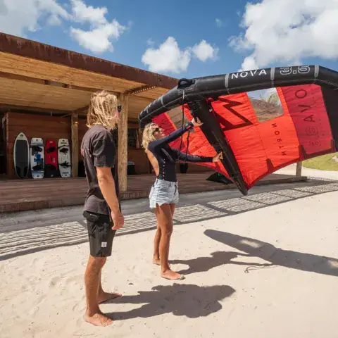 Deux kitesurfeurs préparant une aile devant le local