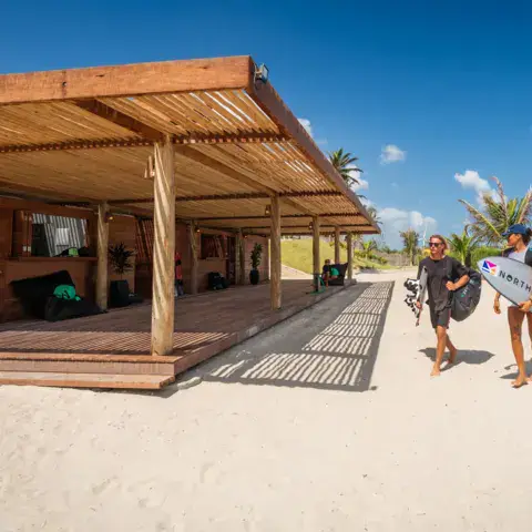 Local en bois sur le sable, kitesurfeurs avec leurs planches