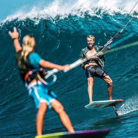 Deux riders de kitesurf devant une vague