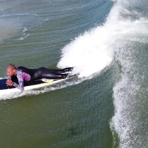 Surfeur allongé sur sa planche dans une vague
