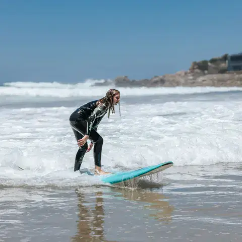 Surfeuse dans l'écume sur une planche