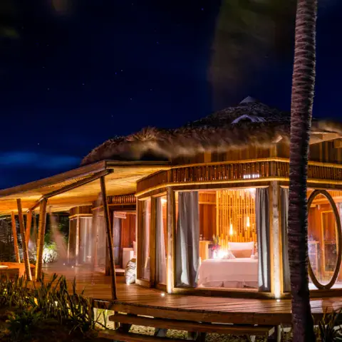 Bungalow éclairé de nuit au milieu de la végétation
