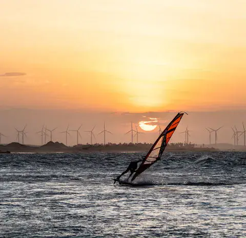 Windsurfeur au coucher du soleil, éoliennes à l'horizon