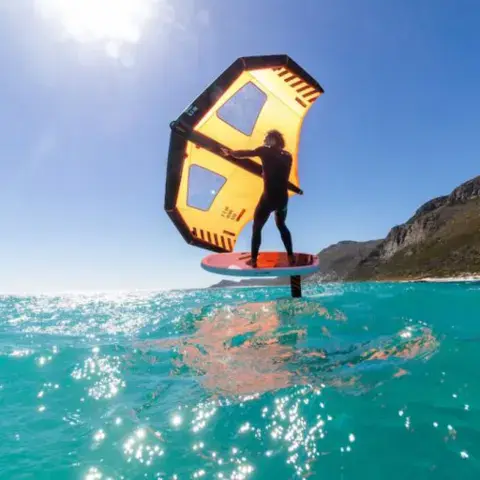 Pratiquant de wing foil au-dessus de l'eau turquoise