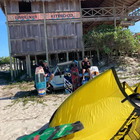Bâtiment sur pilotis avec kite et planche au premier plan