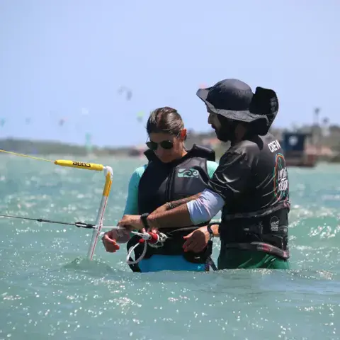 Instructeur guidant un élève dans l'eau, kite en main