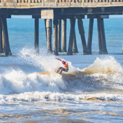 Surfeur dans les vagues près d'une jetée