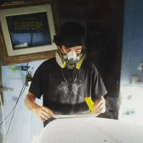 Artisan au travail sur une planche, avec masque de protection