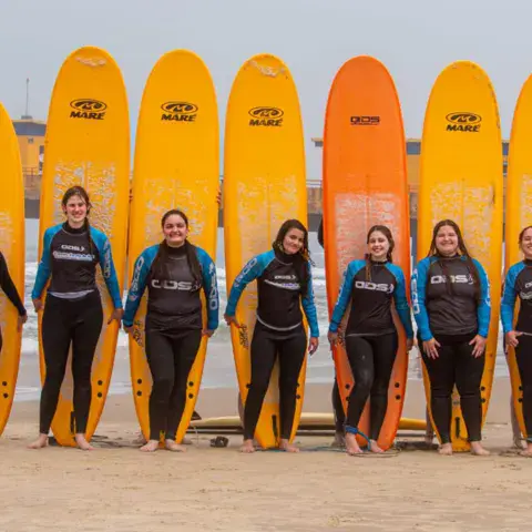 Équipe de moniteurs alignée avec les planches sur la plage