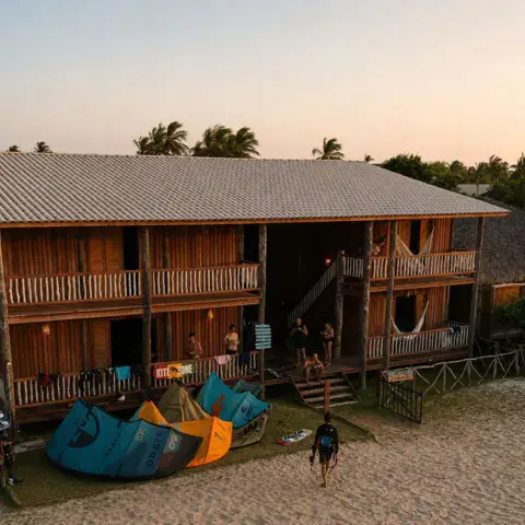 Maison en bois face à la plage, kites étalés devant