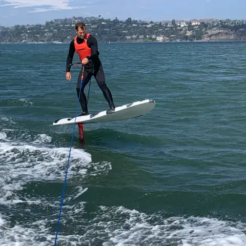 Élève sur une planche de foil tractée derrière le bateau
