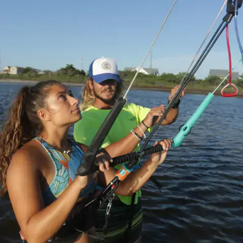 Moniteur et élève avec une barre de kite dans l'eau