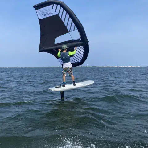 Wing foil sur l'eau avec une aile sombre
