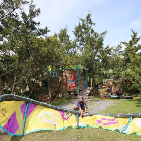 Aile de kite étalée sur la pelouse devant l'atelier