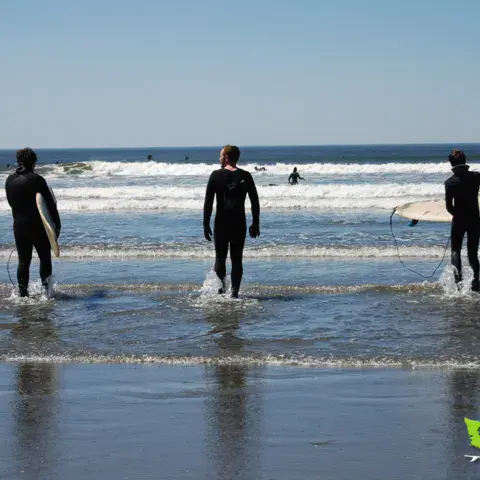 Trois surfeurs entrant dans l'eau avec leur planche