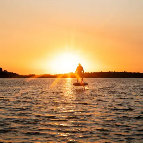 E-foil au coucher du soleil sur un plan d'eau