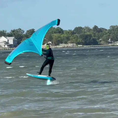Rider de wing foil avec une aile turquoise