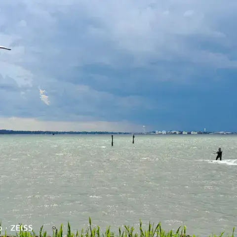 Kitesurfeur au loin sur un plan d'eau agité