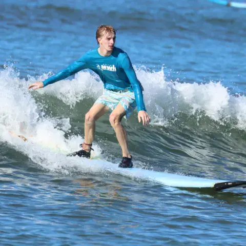 Surfeur debout sur une vague pendant un cours