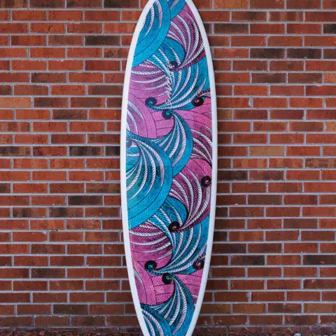 Planche de surf décorée, adossée à un mur de briques