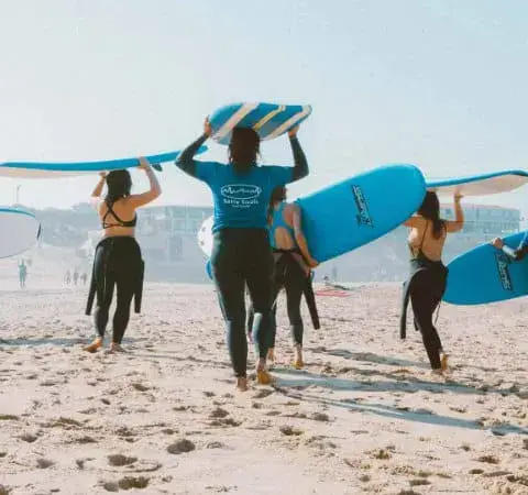 Groupe de surfeurs portant leurs planches sur la plage