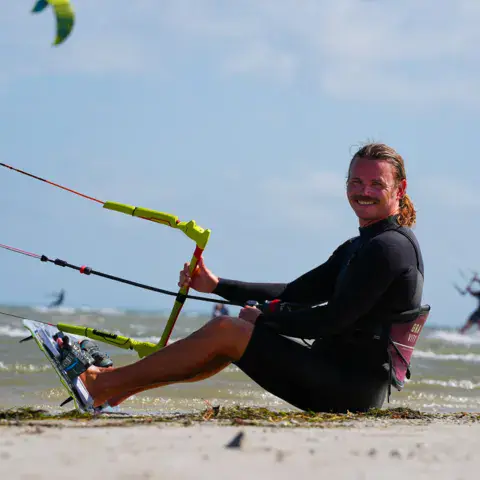 Kitesurfeur assis sur la plage avec sa barre