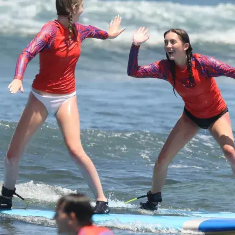 Élèves debout sur leur planche dans les vagues