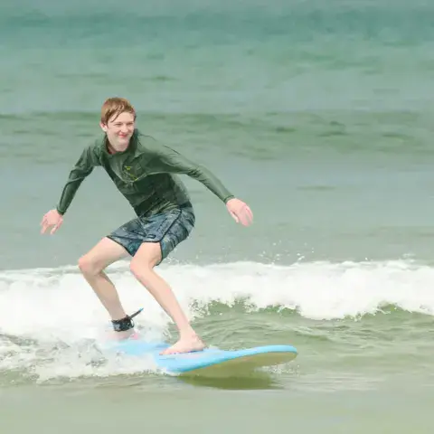 Élève de surf debout sur une planche dans les vagues