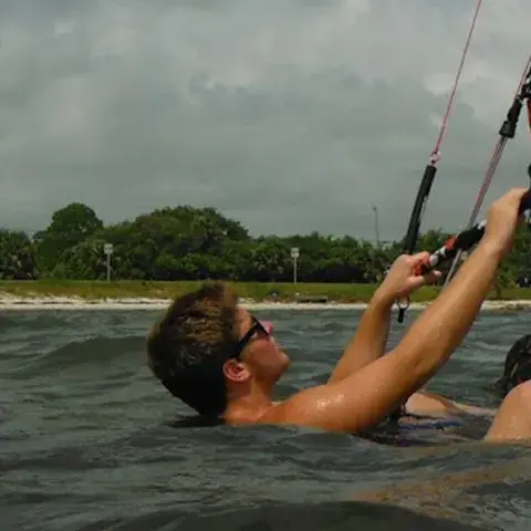 Élève dans l'eau avec sa planche et sa barre de kite