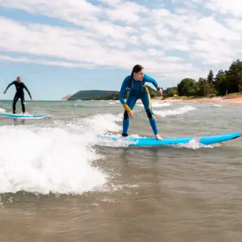 Élève debout sur sa planche dans les vagues du lac