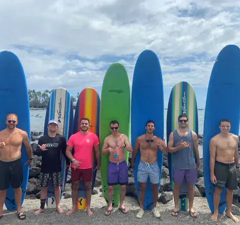 Groupe d'élèves alignés devant leurs planches, sur la côte de lave
